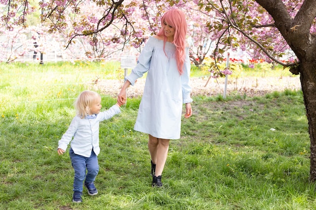 Beautiful young mother walks with a small son in the park in spring