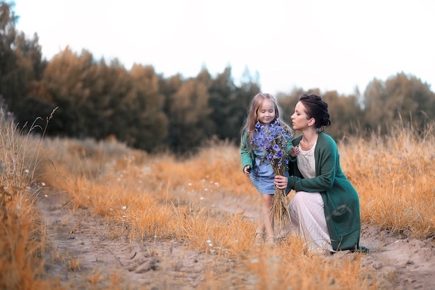 Beautiful young mother with daughter walking on a road