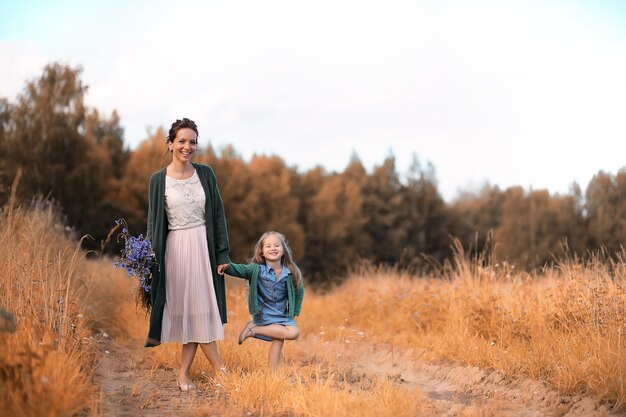 Beautiful young mother with daughter walking on a road