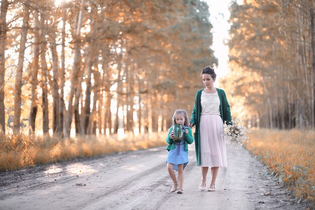 Beautiful young mother with daughter walking on a road