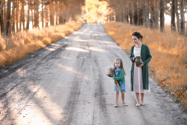 Beautiful young mother with daughter walking on a road