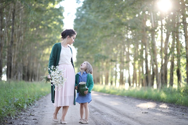 Beautiful young mother with daughter walking on a rural road