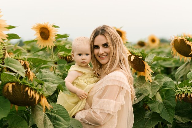 A beautiful young mother with her cute daughter in a field of sunflowers