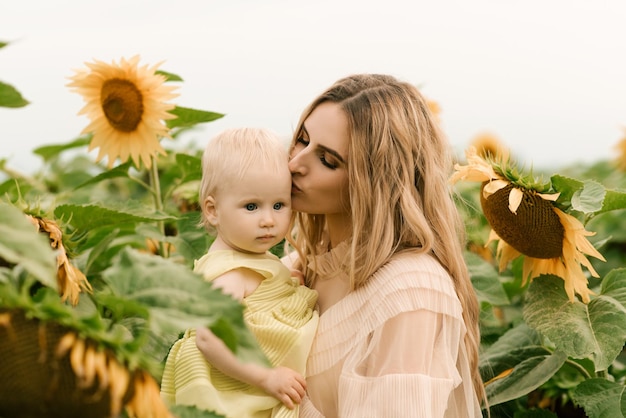 A beautiful young mother with her cute daughter in a field of sunflowers