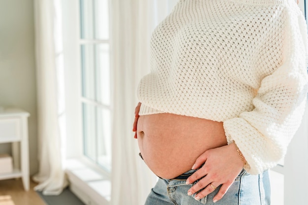 A beautiful young pregnant woman in a bright modern interior Tender concept of motherhood