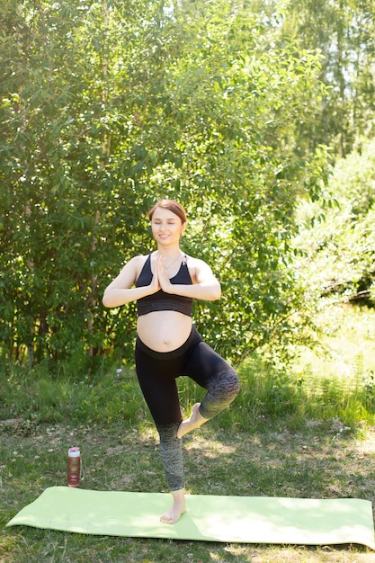 아름다운 젊은 임산부는 임산부 건강을 위한 자연 수업에서 요가 명상 훈련 및 스포츠를 합니다.