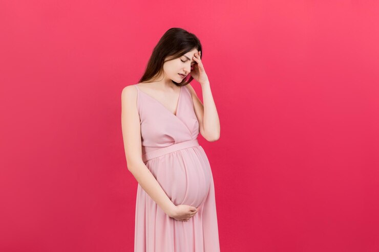 Photo 美しい若い妊婦が色の背景で頭痛を感じ孤立しているストレスを抱えた妊婦または母親の問題