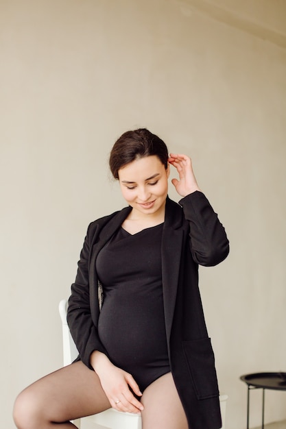 Beautiful young pregnant woman posing in studio in dress