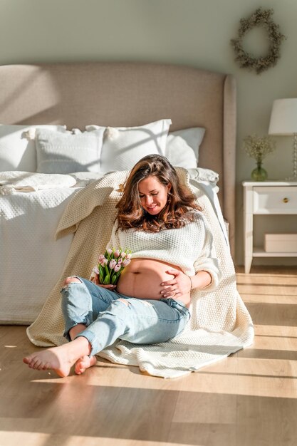 Beautiful young pregnant woman sitting in a beautiful bedroom
