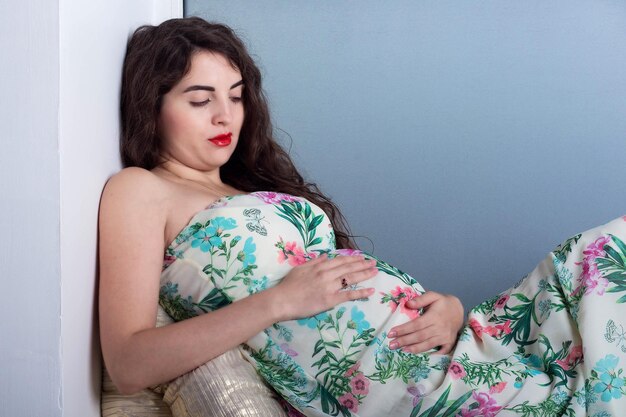 Beautiful young pregnant woman with curly hair in a long dress