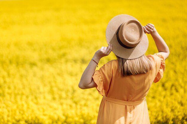 Foto bella giovane donna incinta in un campo di colza giallo.