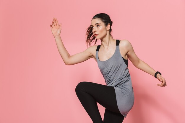 beautiful young pretty fitness woman running make sport exercises isolated over pink wall