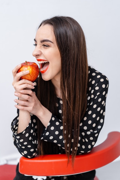 Beautiful young pretty woman, model, girl with red lips. Girl eating an apple, smiling. Closeup