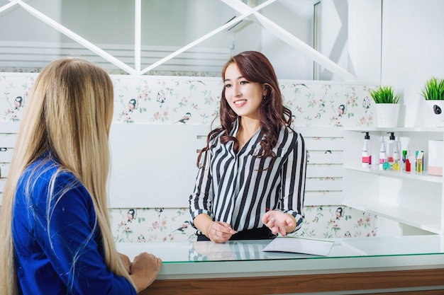 Photo beautiful young receptionist girl with a smile at the reception meets customers in the salon