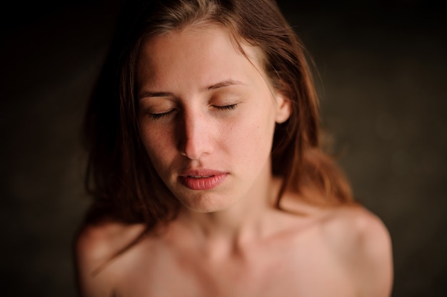 Beautiful young redhead girl in the water cave with closed eyes