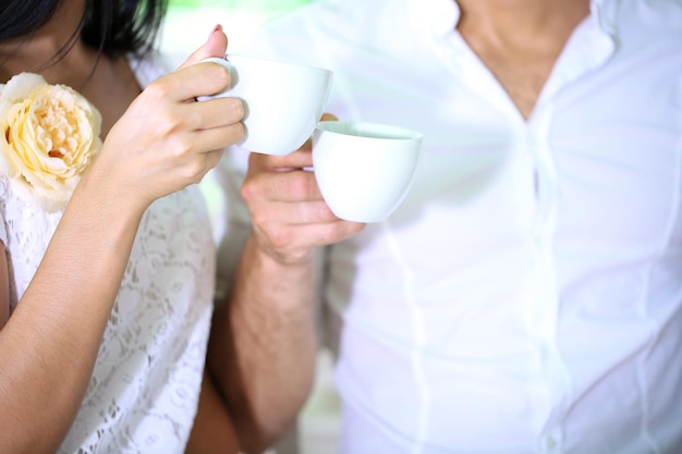 Beautiful young romantic couple holding cups of coffee close up