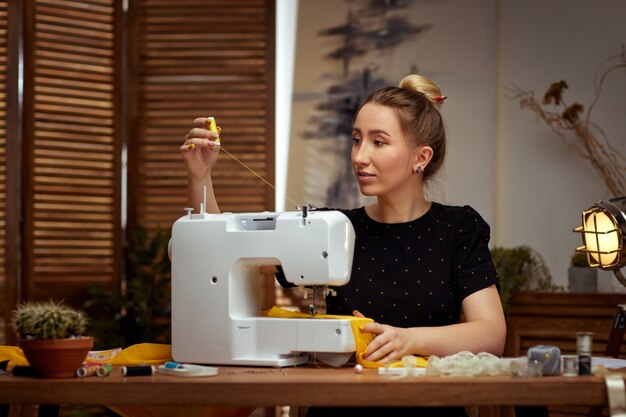 Beautiful young seamstress working on sewing machine