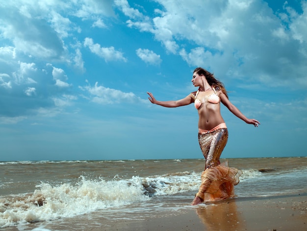해변에서 세련된 가운을 입은 아름다운 젊은 섹시한 패션 모델