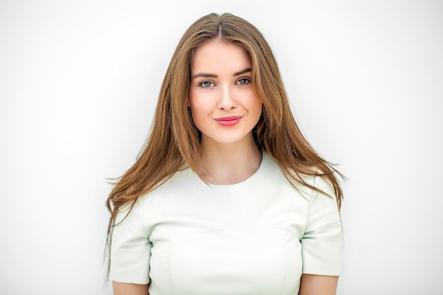 美しいセクシーな若い女性が白い壁にポーズをとっている