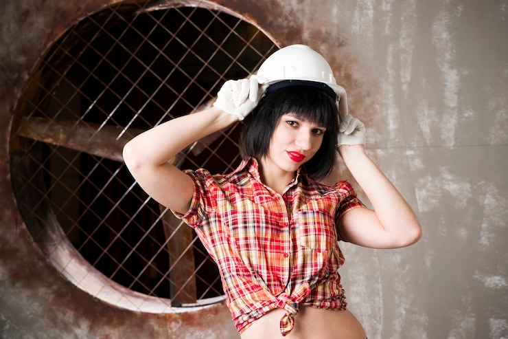 Photo beautiful young sexy woman in a white helmet posing with construction equipment
