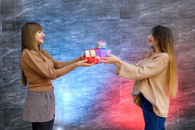 Beautiful young sisters. Christmas and New Year celebration. Two beautiful sisters exchanging with present boxes