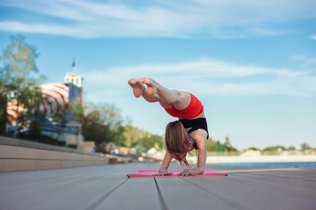 Bella giovane ragazza magra che fa yoga o esercizio ginnico in riva al lago stile di vita sano