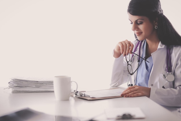 Beautiful young smiling female doctor sitting at the desk