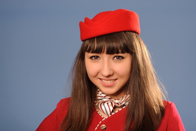 Foto bella giovane assistente di volo sorridente in uniforme