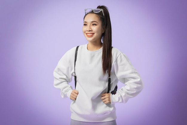 Beautiful young smiling girl with backpack isolated on violet