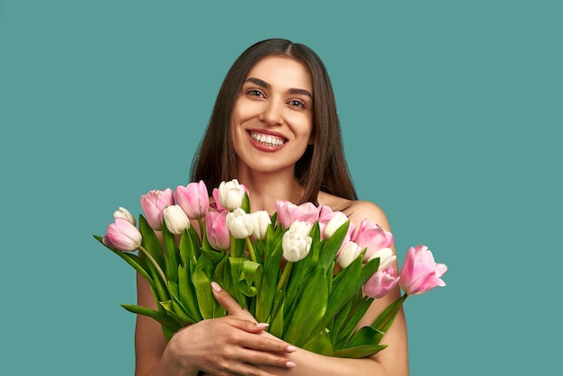 Beautiful young smiling girl with bouquet of white and pink tulips concept beauty spring prosperity