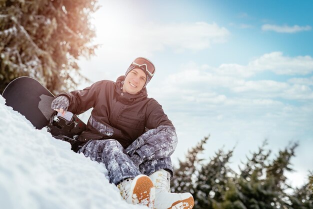 Beautiful young smiling man with snowboard enjoying a sunny winter day. Looking at camera.