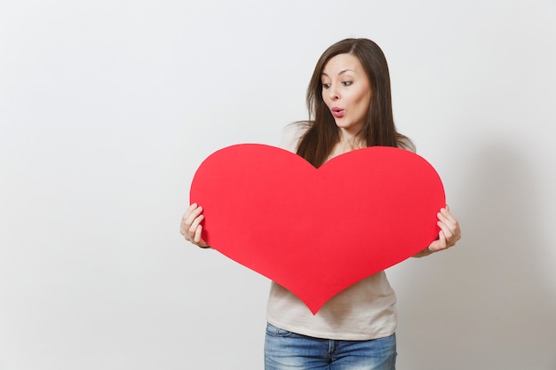 Beautiful young smiling woman holding big red heart in hands isolated on white background. Copy space for advertisement. With place for text. St. Valentine's Day or International Women's Day concept.