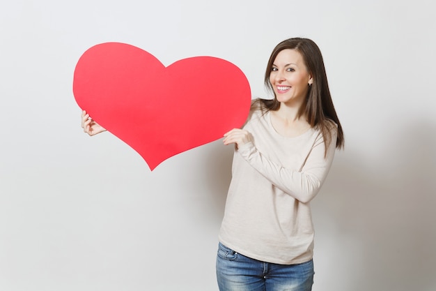 Beautiful young smiling woman holding big red heart in hands isolated on white background. Copy space for advertisement. With place for text. St. Valentine's Day or International Women's Day concept.