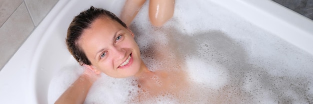 Beautiful young smiling woman lies in bath top view