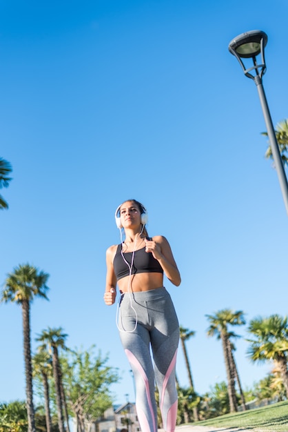 Beautiful young sports Woman running jogging in a park outdoors listening music