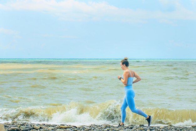 Beautiful young sportswoman runs along the seashore on a sunny day