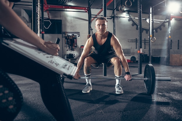 Beautiful young sporty couple training workout in gym together