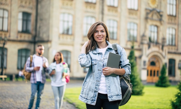 Beautiful young student girl with a backpack and books by the university