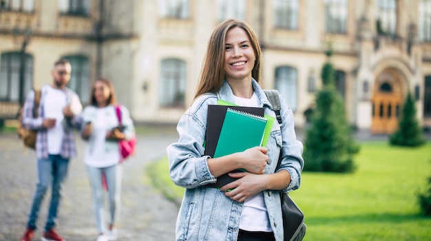 Beautiful young student girl with a backpack and books by the university