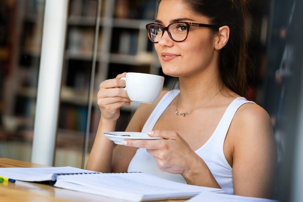 Bella giovane studentessa con tanti libri, che studia o si prepara per gli esami