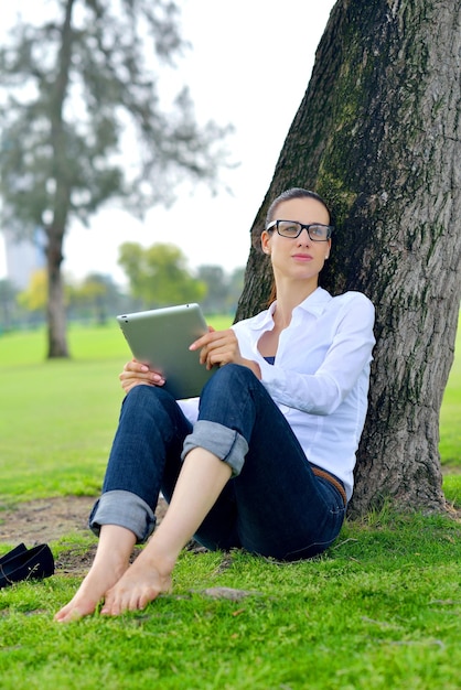 公園でタブレットで勉強する美しい若い学生女性