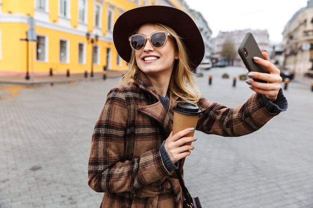 Beautiful young stylish blonde woman wearing a coat walking outdoors