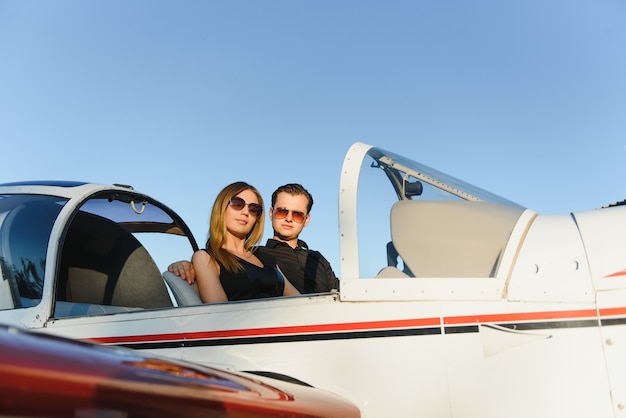 Beautiful young stylish couple in official clothes standing in private plane