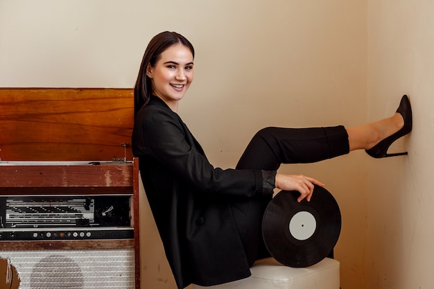 A beautiful young stylish woman near a vintage record player