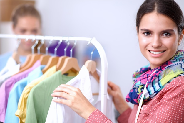 Beautiful young stylist woman near rack with hangers