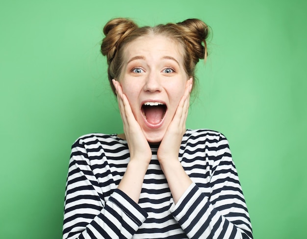 Beautiful young surprised woman over green background