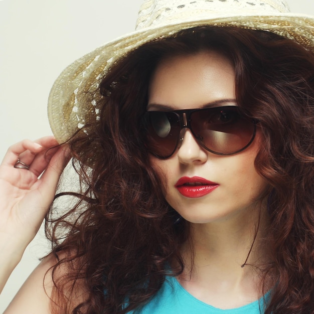 Beautiful young surprised woman wearing hat and sunglasses