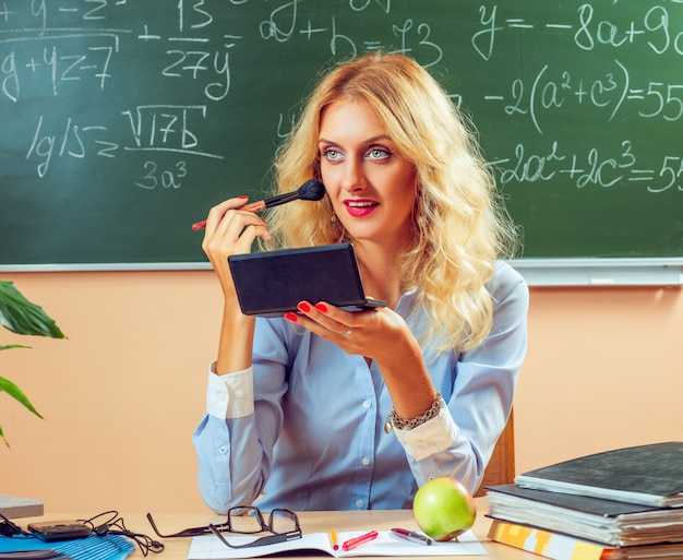 Beautiful young teacher making-up between the classes