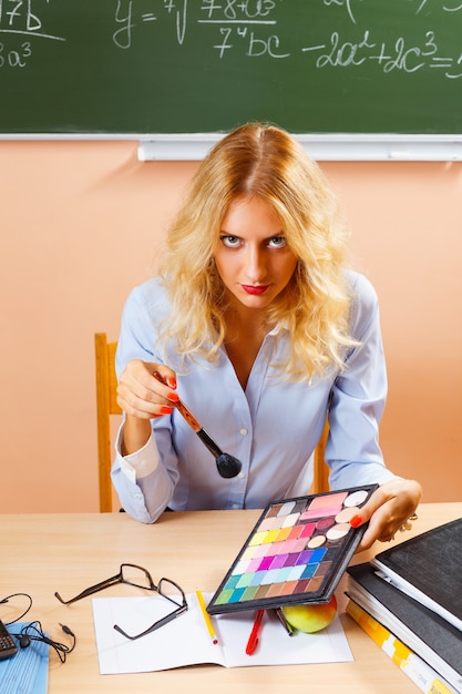 Beautiful young teacher making-up between the classes