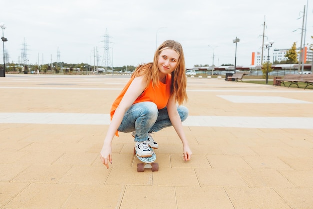 A beautiful young teenage girl rides a skateboard in sunny weather generation z